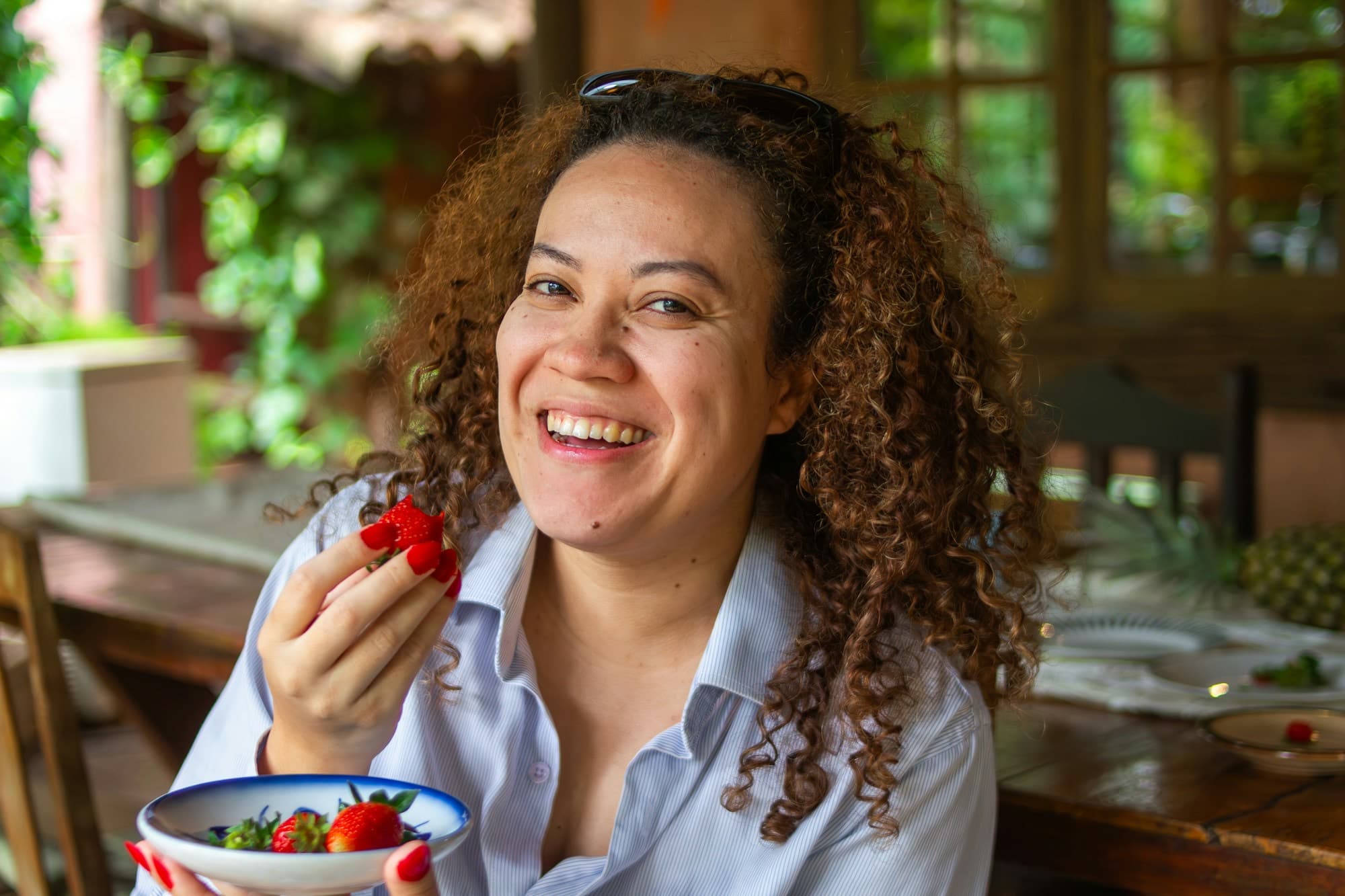 A woman laughing over a bowl of strawberries
